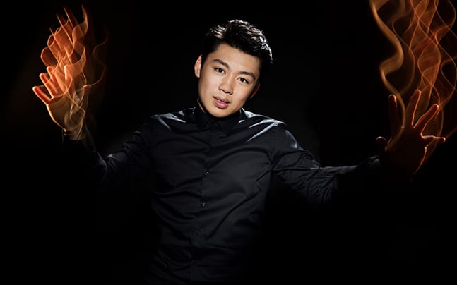 George Li is pictured wearing all black with the focal point as flames coming from his open, outstretched hands.