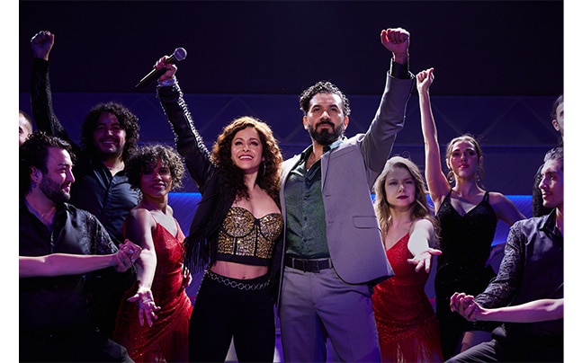 Gloria & Emilio Estefan standing in front of Cast with Fist in the Air