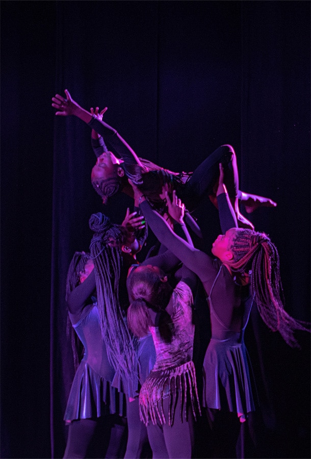girl dancers lifting up girl in air with purple lighting