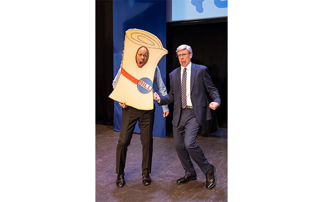 Man dressed as a bill on stage with politician