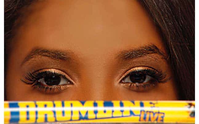 Close up of Woman's Eyes and Drumstick that says DRUMLINE LIVE