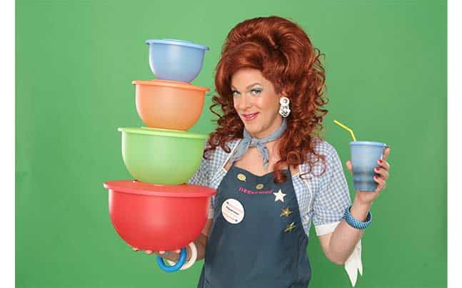 Dixie in an apron holding stacked turperware and a glass