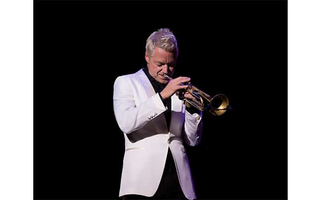 Chris Botti playing trumpet, facing front right, black background