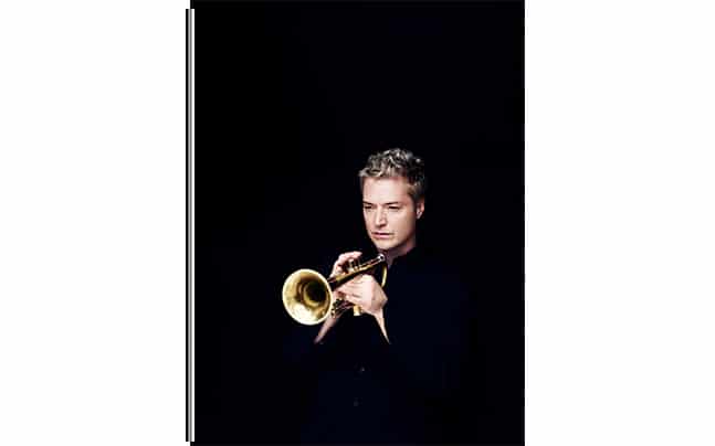 Chris Botti holding his trumpet in a playing position with black background