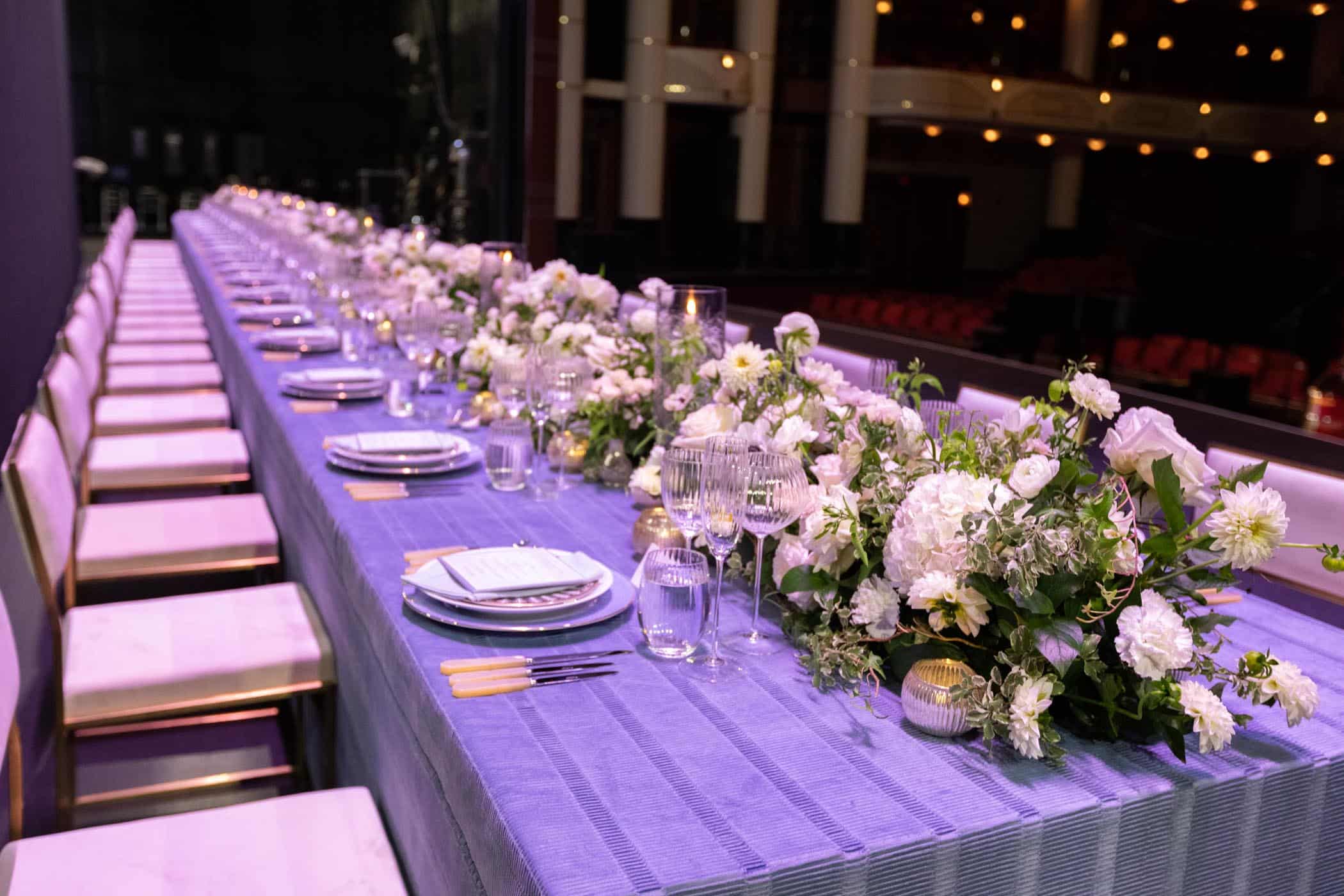 Table adorned with flowers and table settings with Dreyfoos Hall featured in background.