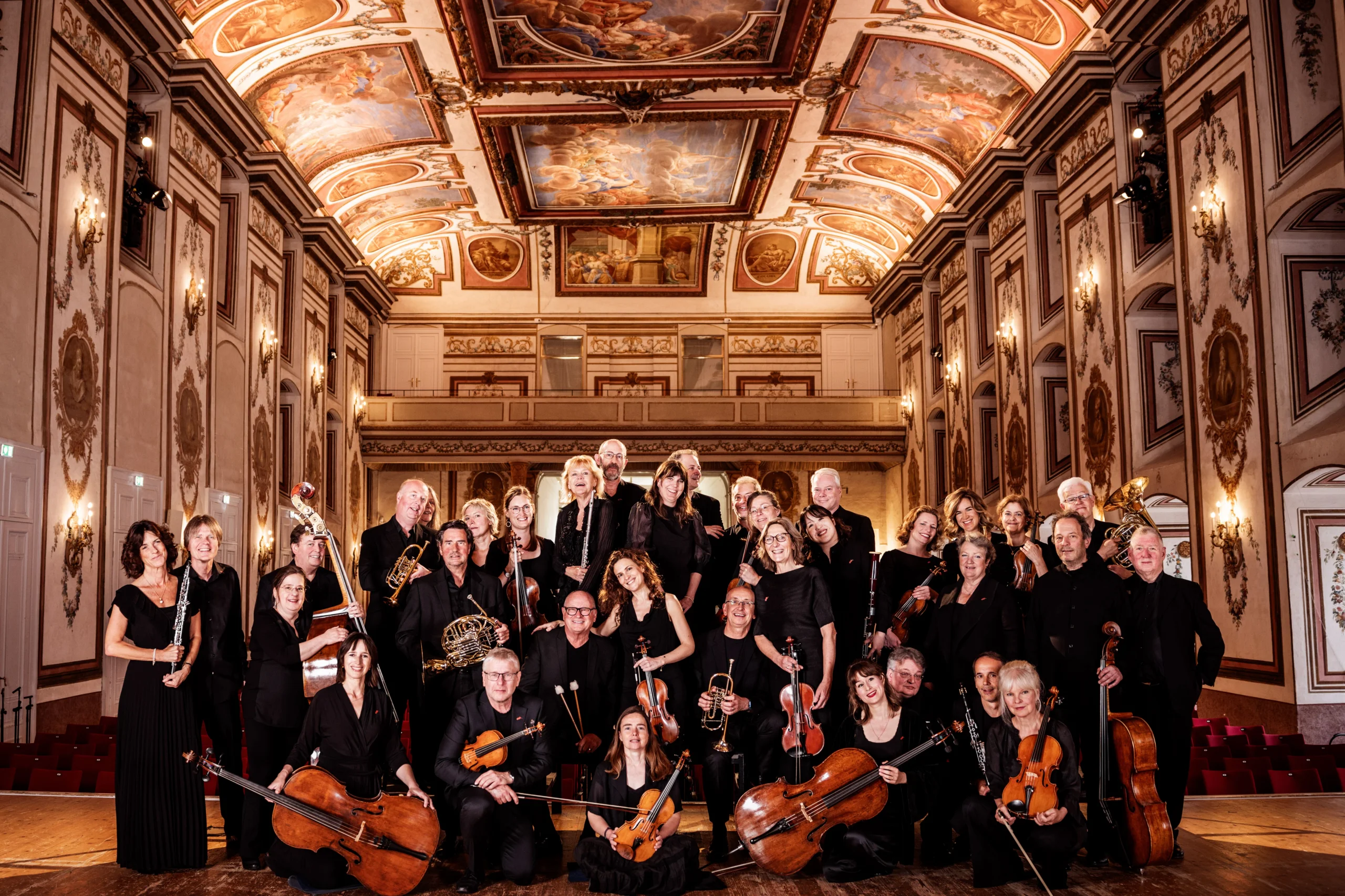 Chamber Orchestra Of Europe in music hall posing with instruments.