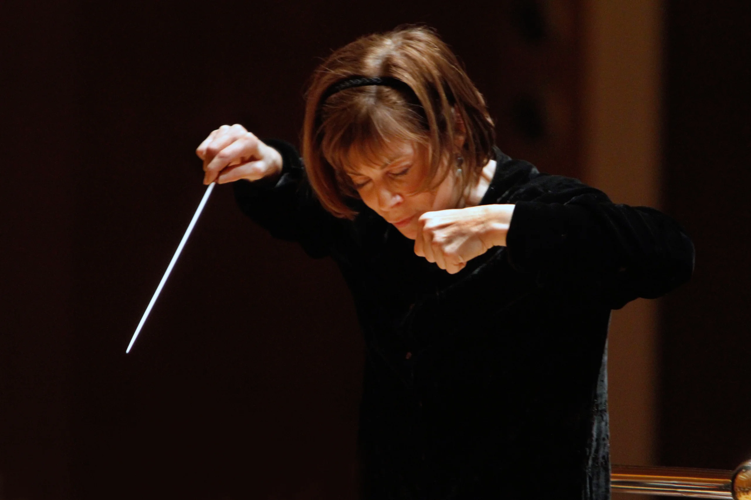 JoAnn Falletta conducting orchestra with batton.