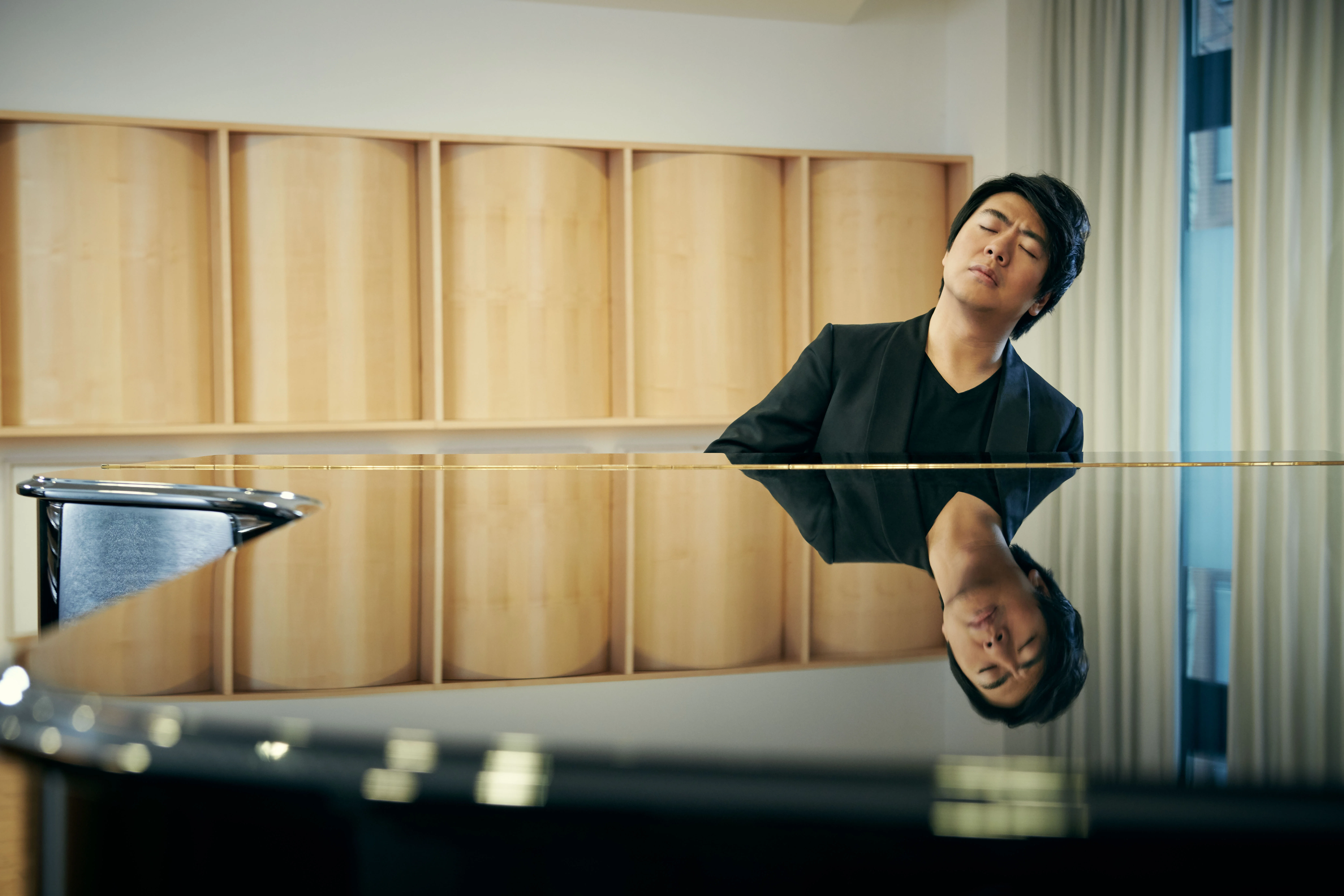 Lang Lang siting at piano playing with eyes closed.