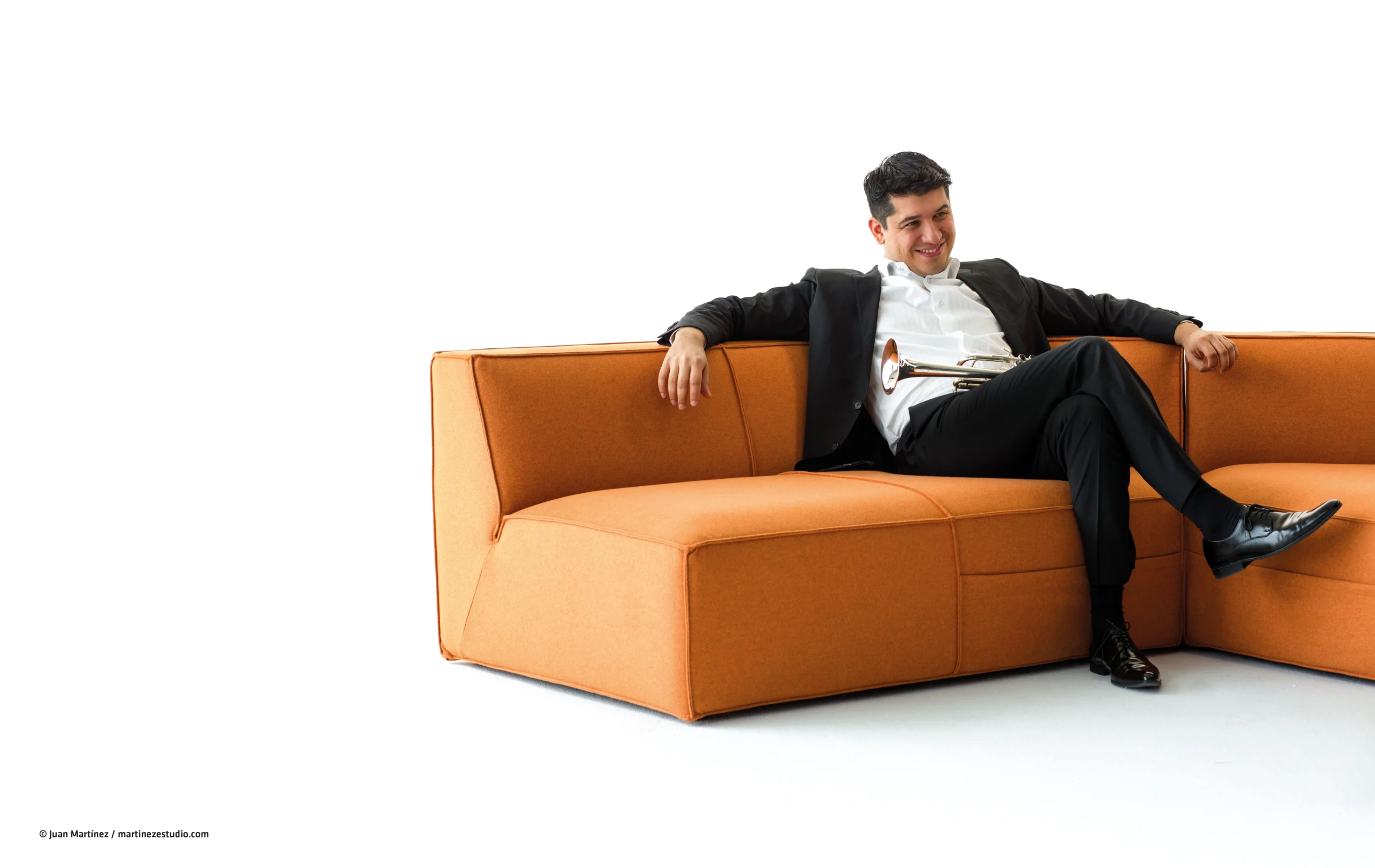 Pacho Flores sitting on a orange colored couch.