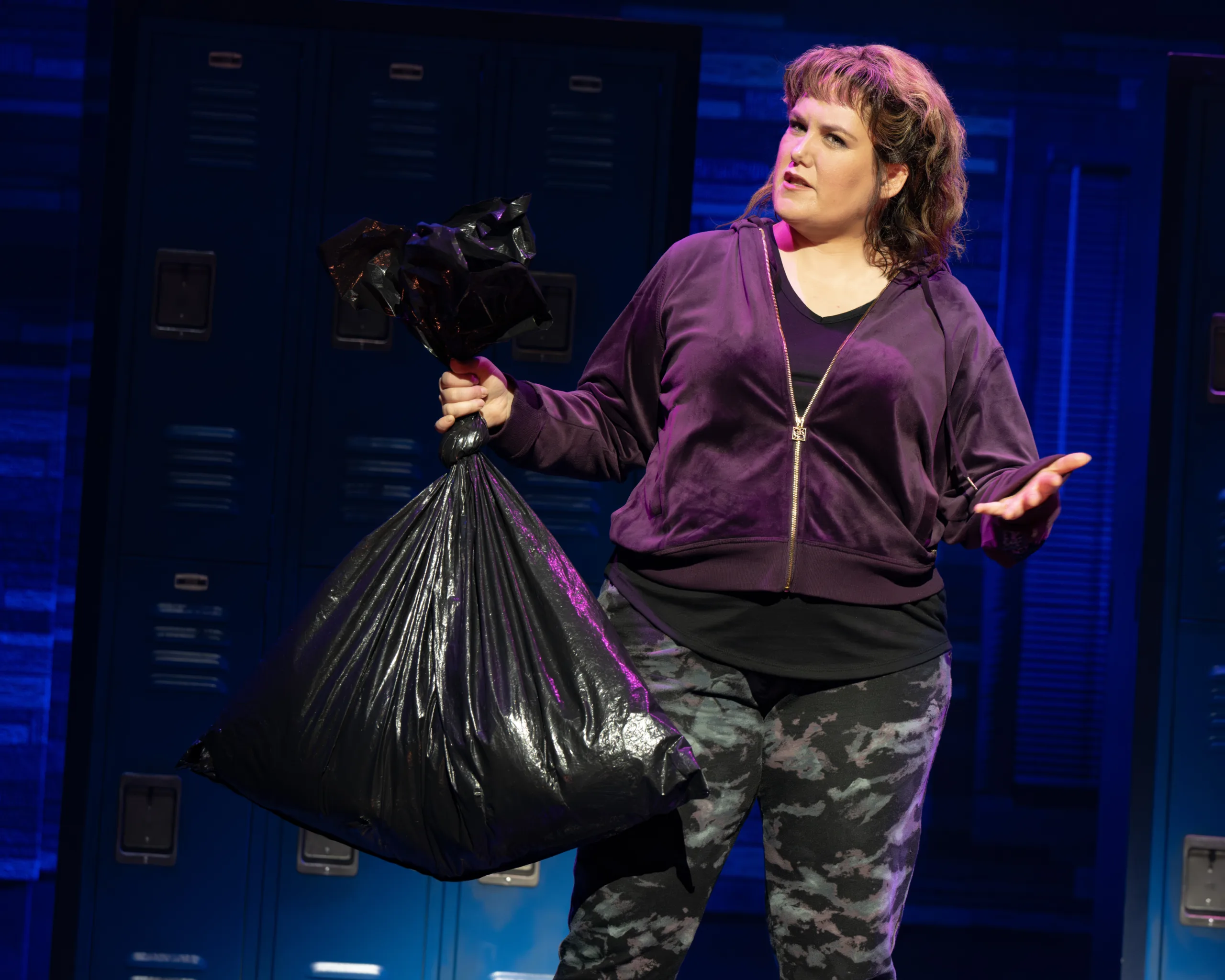 Kimberly in a purple sweatshirt holding a black garbage bag.