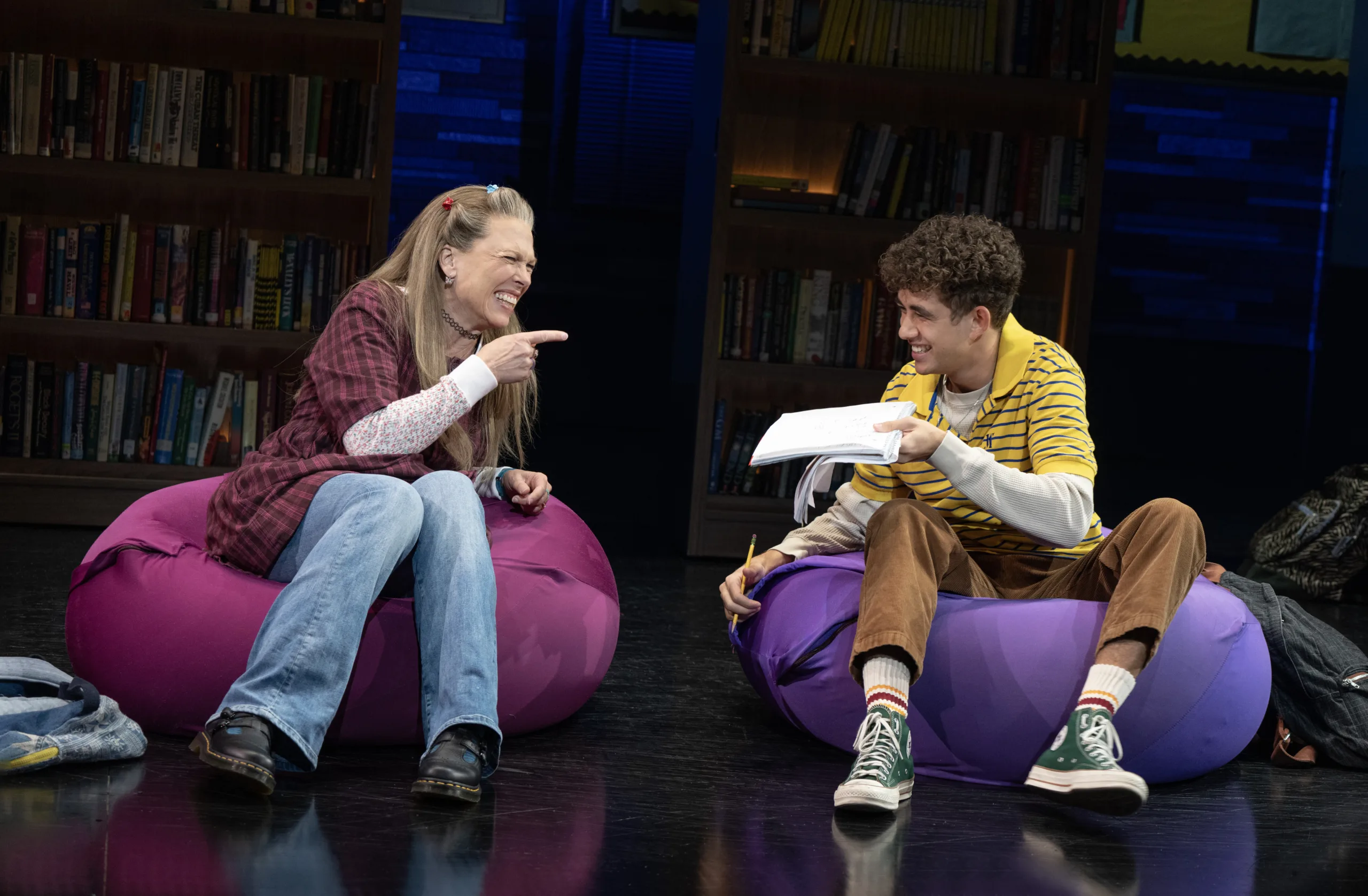Two students sitting on bean bags with one showing the other a book.