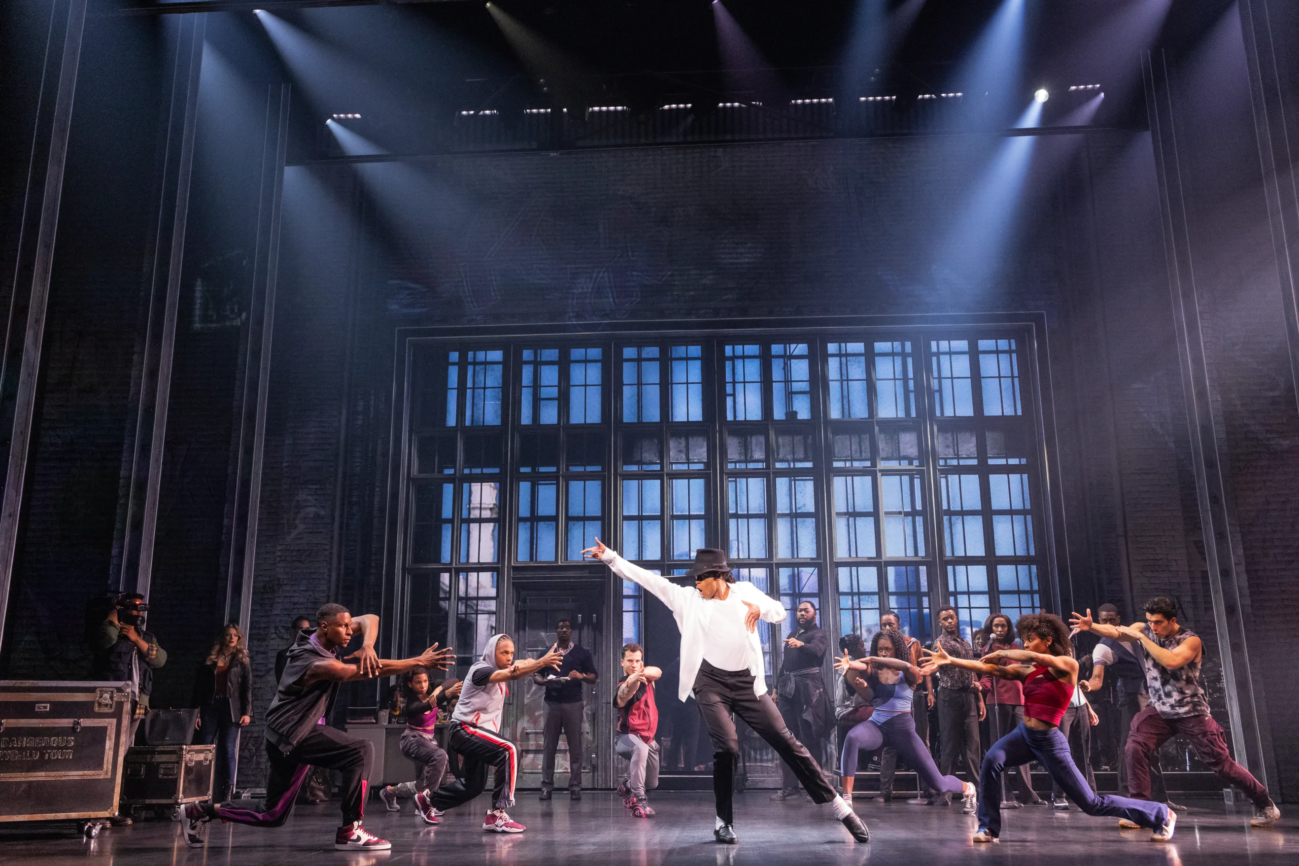 MJ in the middle showing off a dance pose while the company looks on.