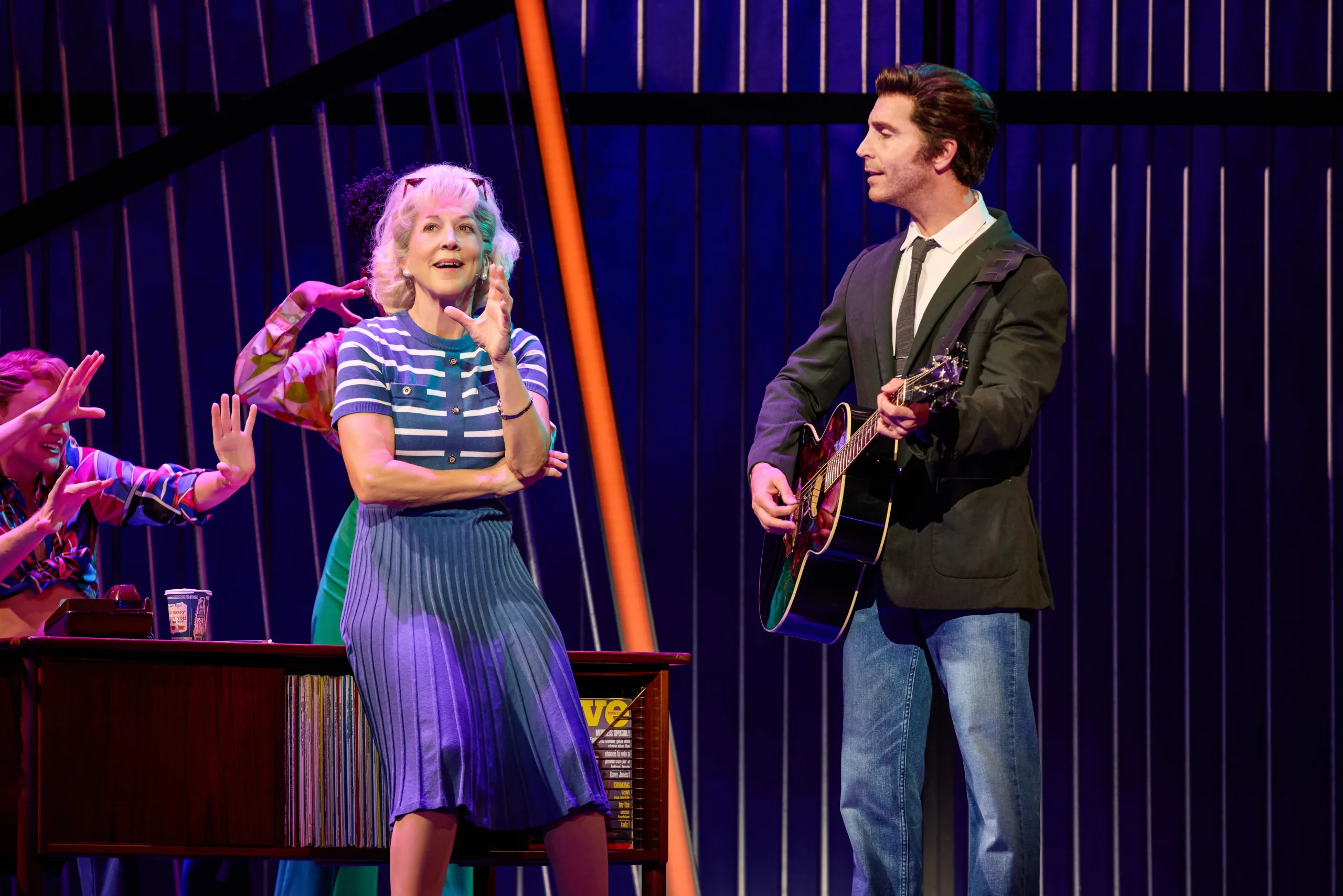Neil holding guitar next to Ellie Greenwich sitting on a desk. 