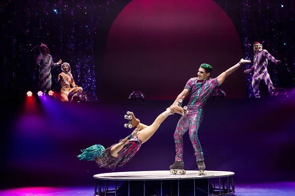 Roller Skating man swinging his skating partner by her leg in a circle. 