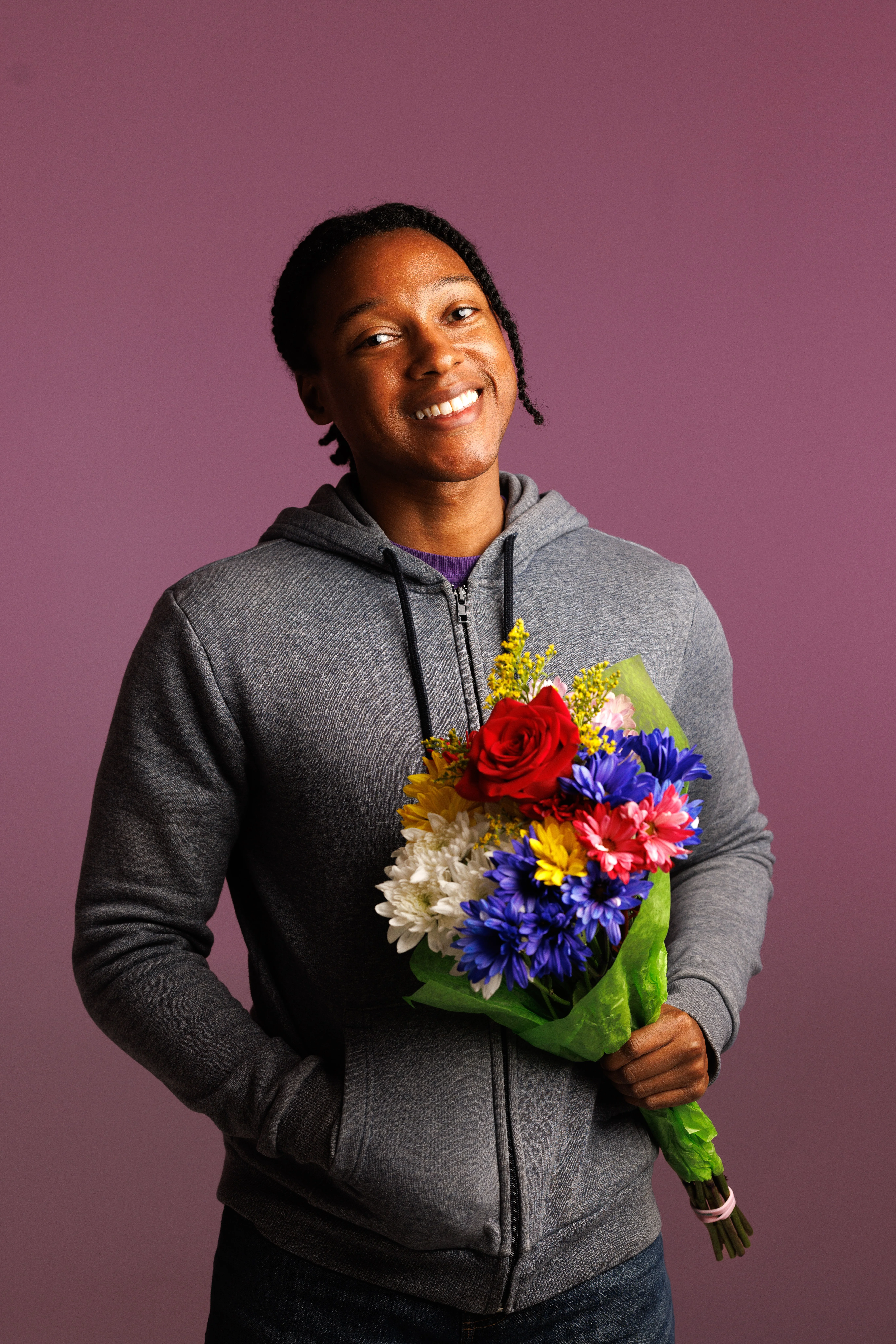 Josh Johnson headshot with him holding bouquet of colorful flowers.