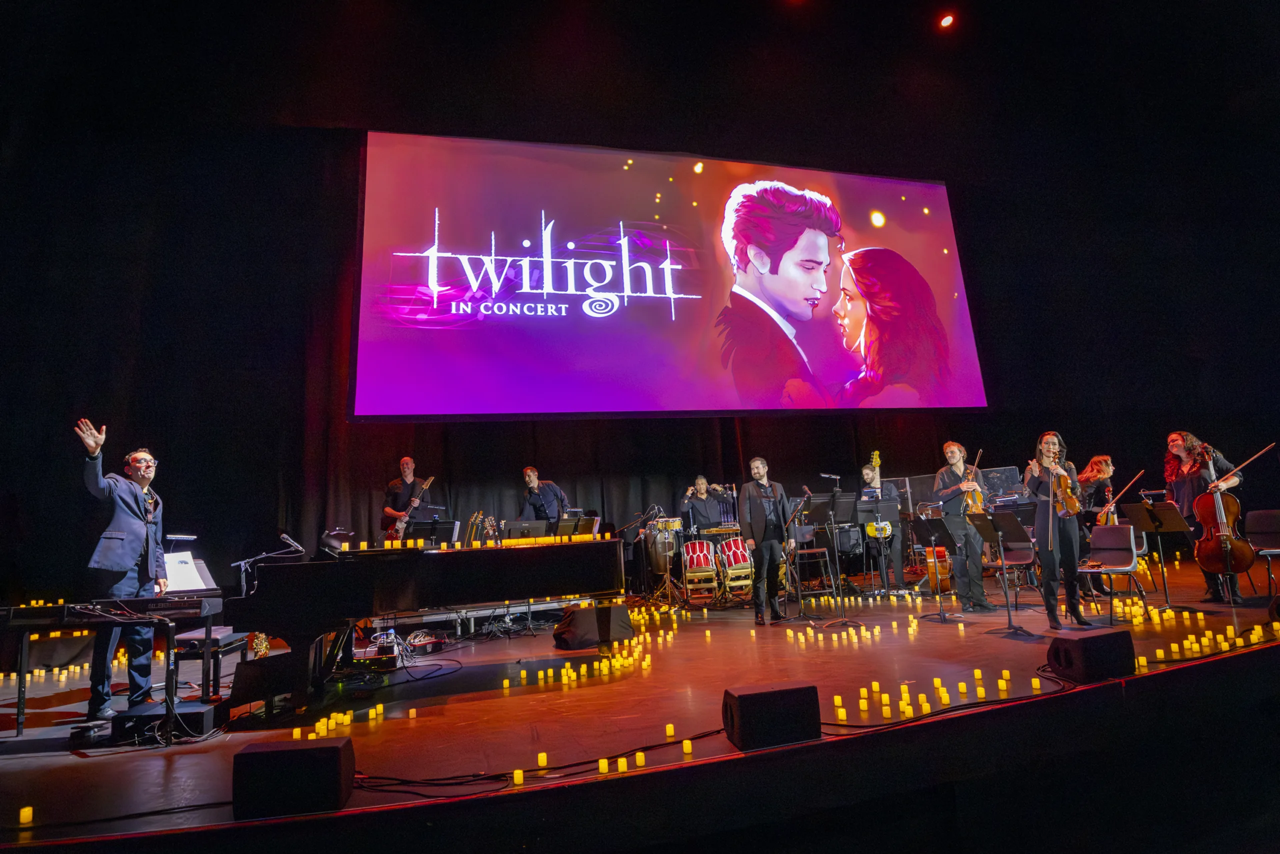 Red and purple poster projected over the stage with cartoon drawings of Edward Cullen and Bella Swan in the center and the white text 