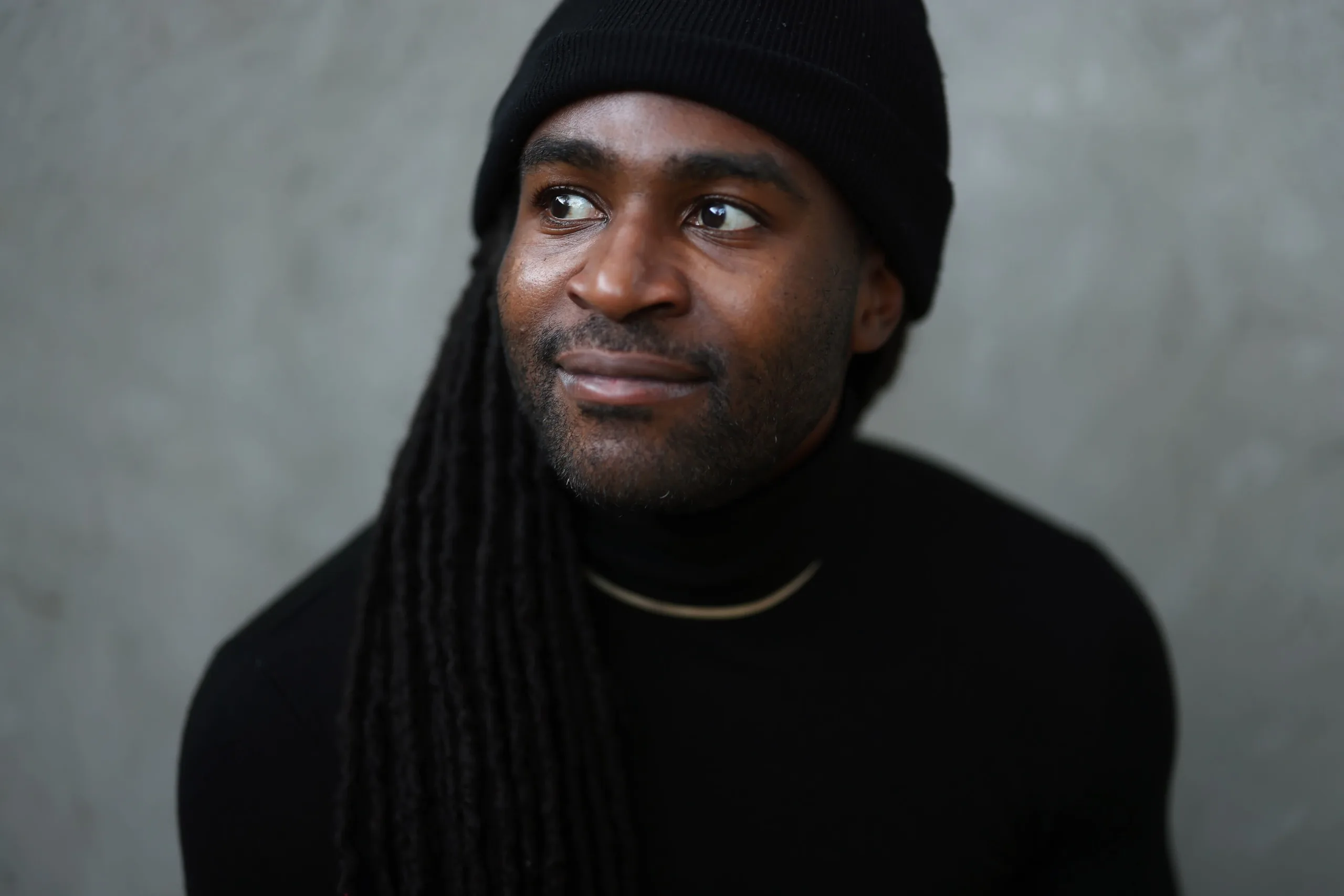 Headshot of a man in black smiling softly just off camera to his right.