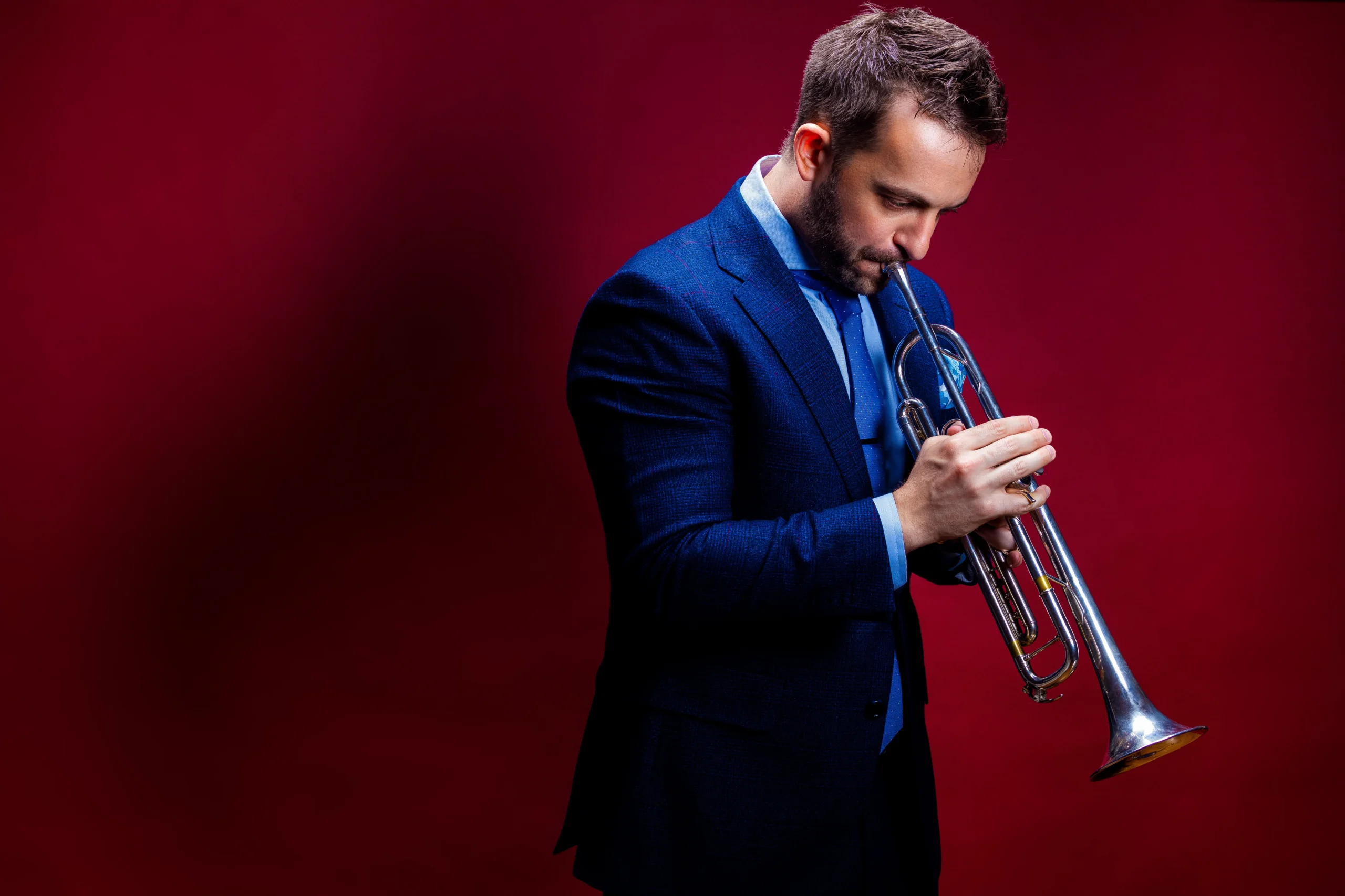Benny Benack III playing trumpet in blue suit.