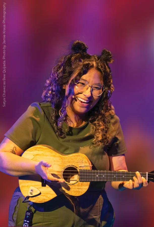 Satya Chavez performs with wooden wind instrument on stage.
