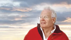 Alexander W. Dreyfoos in red coat with sunset behind him.
