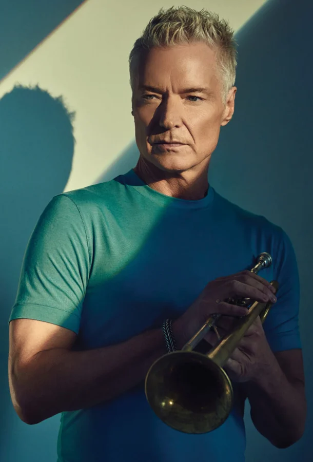Chris Bottti holding trumpet looking serious.
