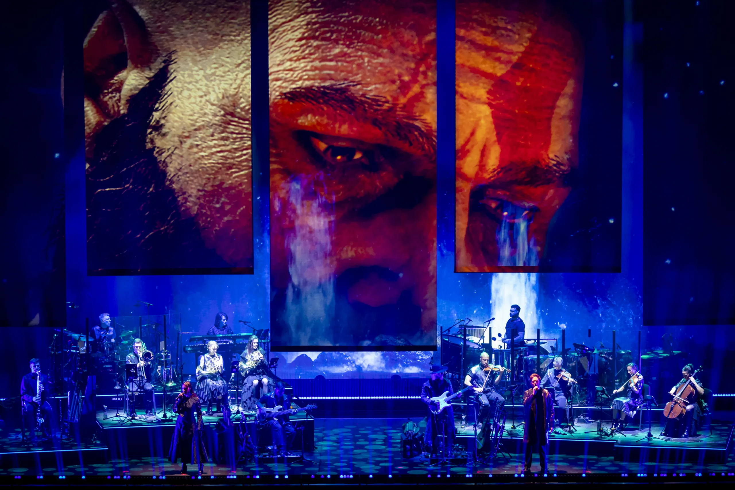 The band on stage in blue light with projections from 