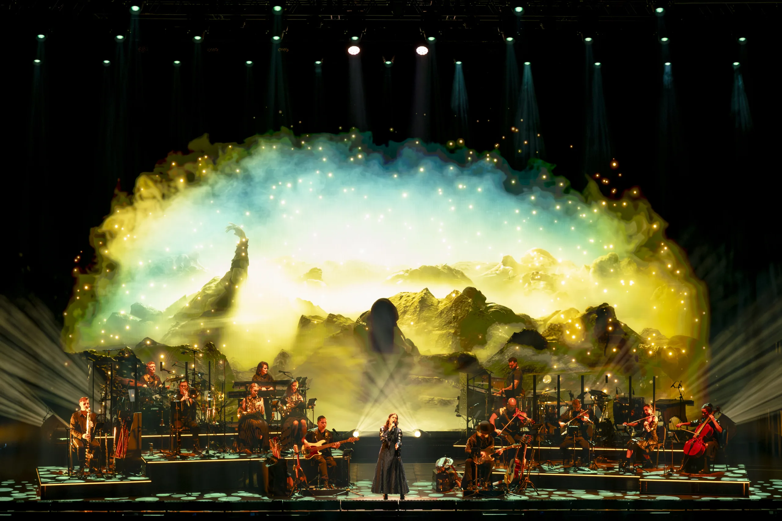 The band on stage in front of a projection of a mountainous horizon from 