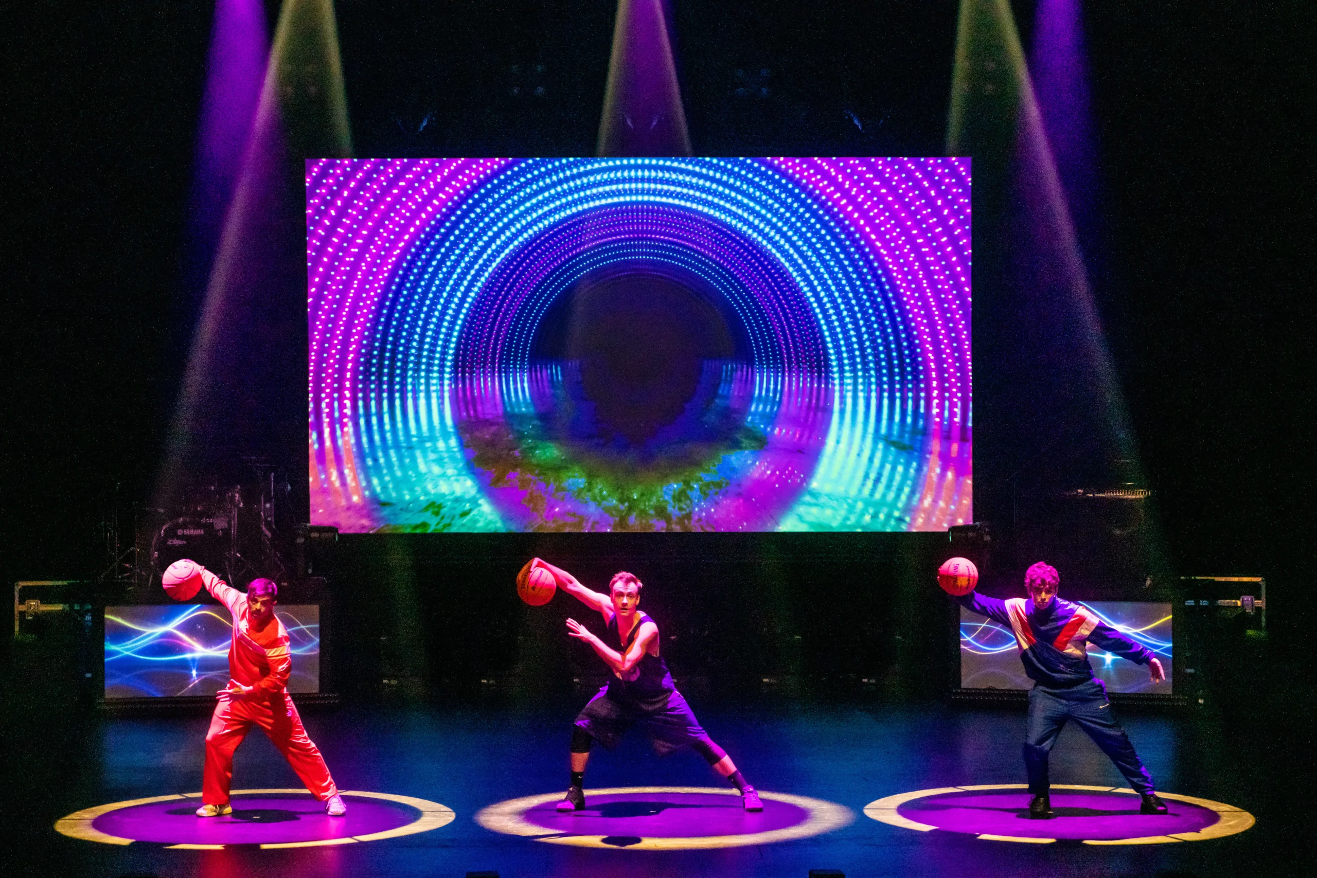 360 Allstars holding basketballs within a circle on stage.