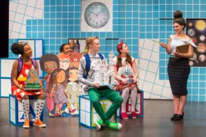 Actors in colorful clothing in a pretend classroom setting