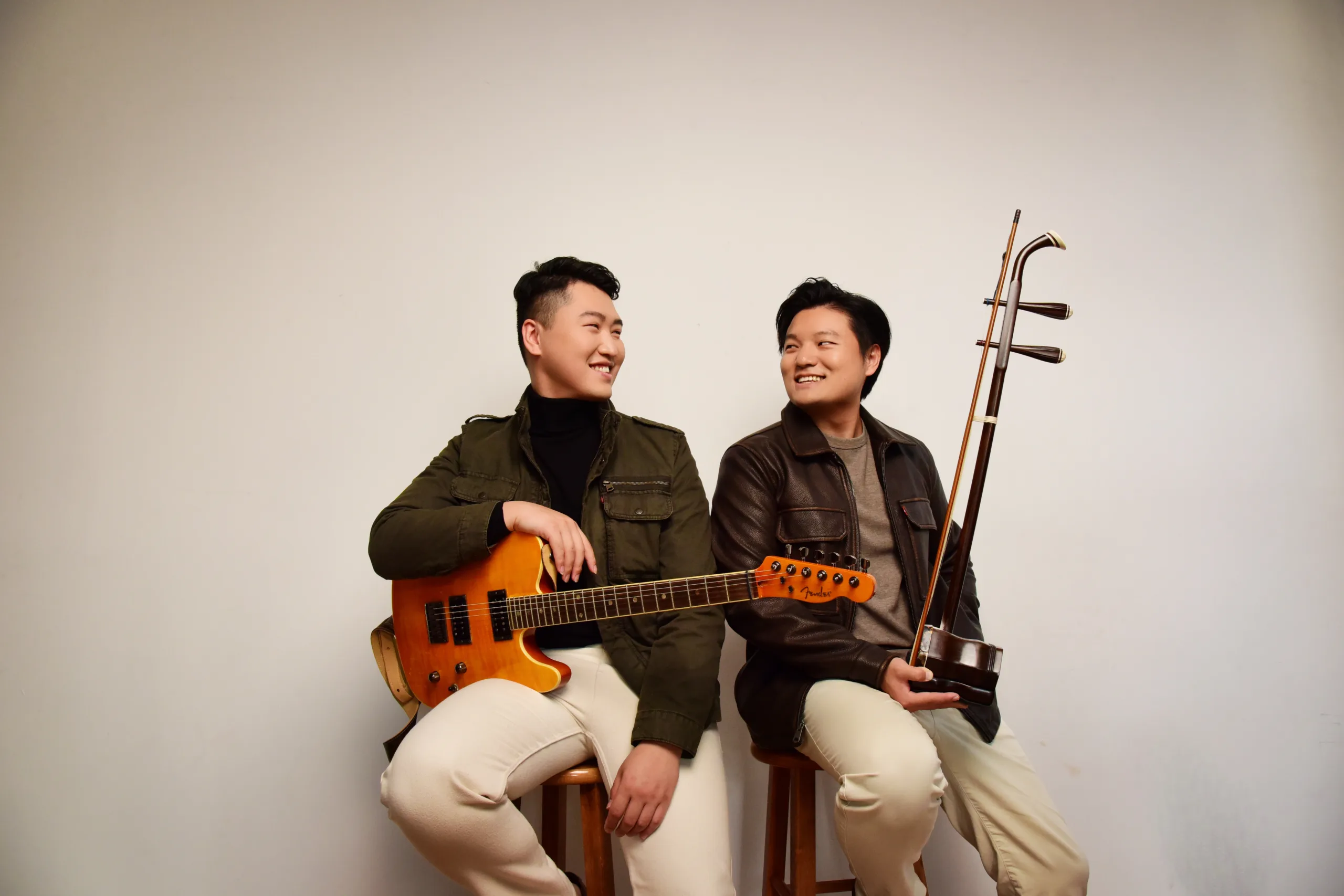 Two members of Arcostrum sitting on stools with their instruments.
