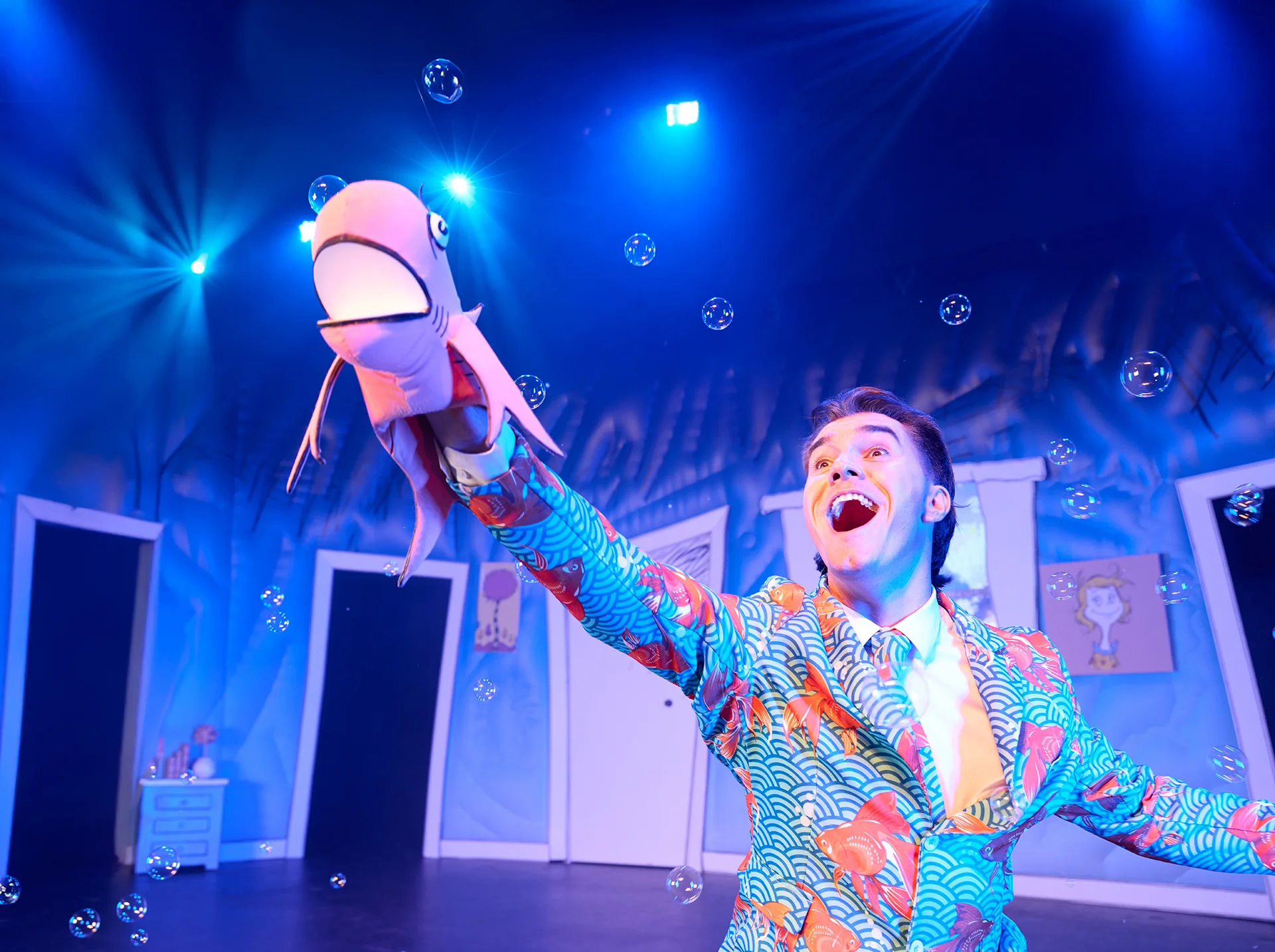 Man puppeteering Fish in the Cat in the Hat set with bubbles floating all around.