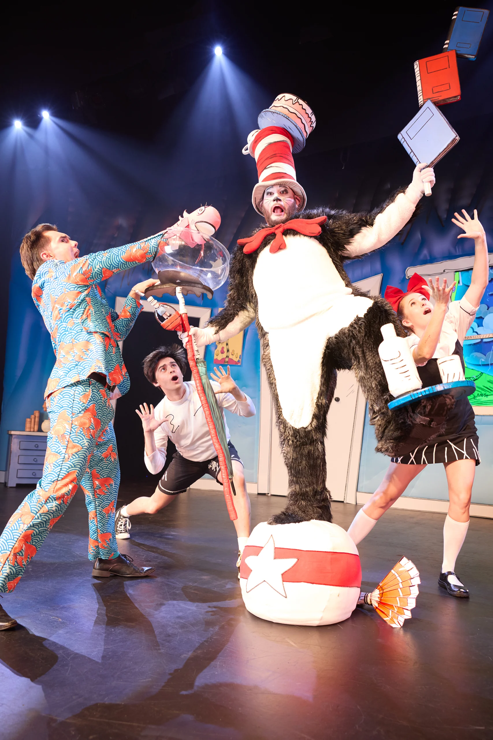 The Cat in the Hat cast in costume on stage posing all together with the Cat in the middle gesturing widely.
