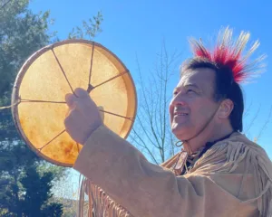 Man in Native American wear holding a drum