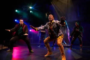 Two men on a colorful stage, crouched down and talking