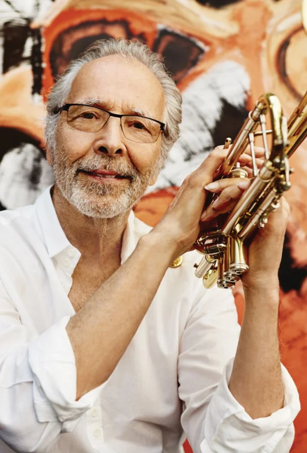 Photo by Dewey Nicks Herb Alpert holding trumpet behind a colorful mural.