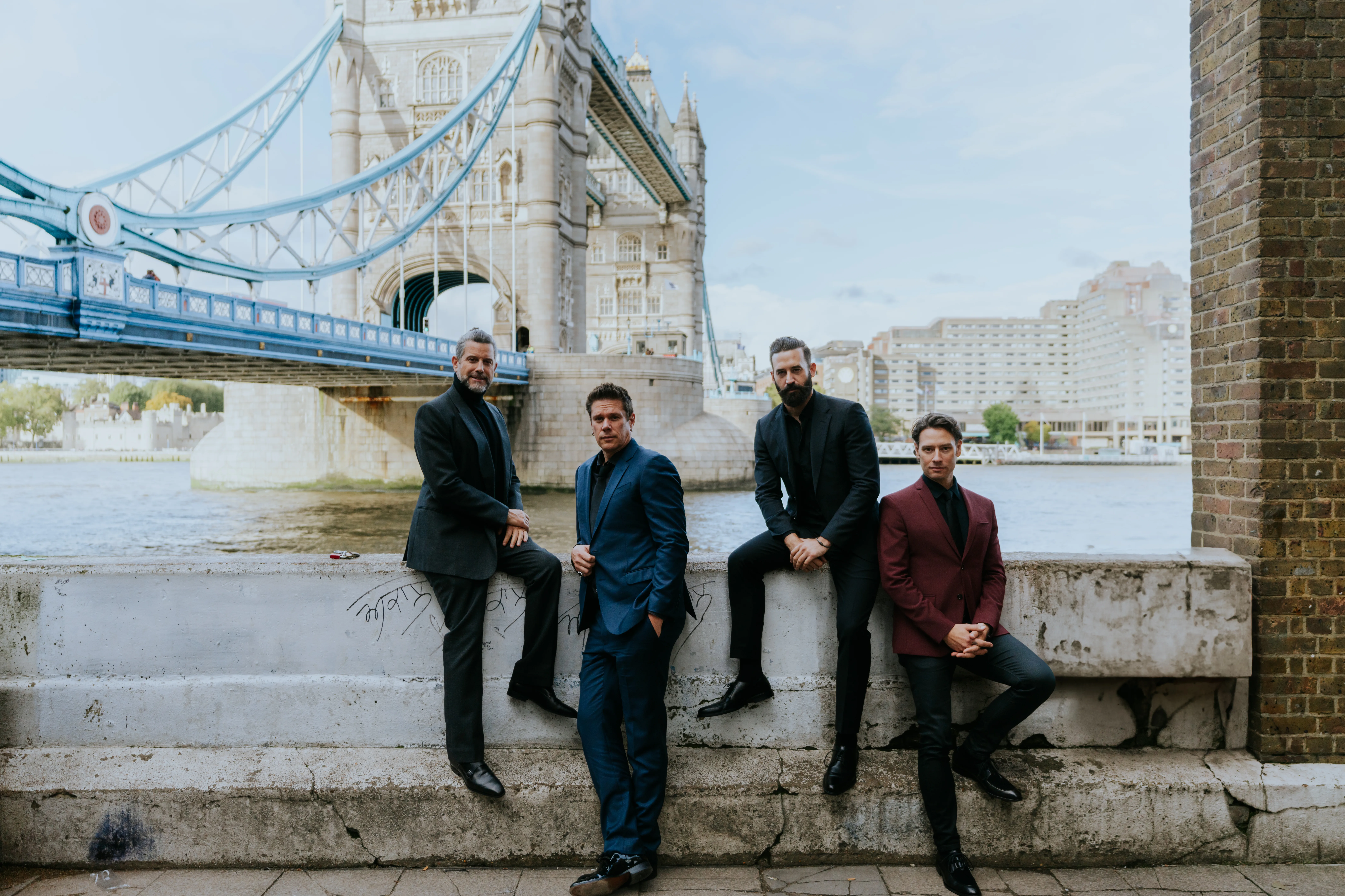 Four member of Il Divo posing together on a bridge.