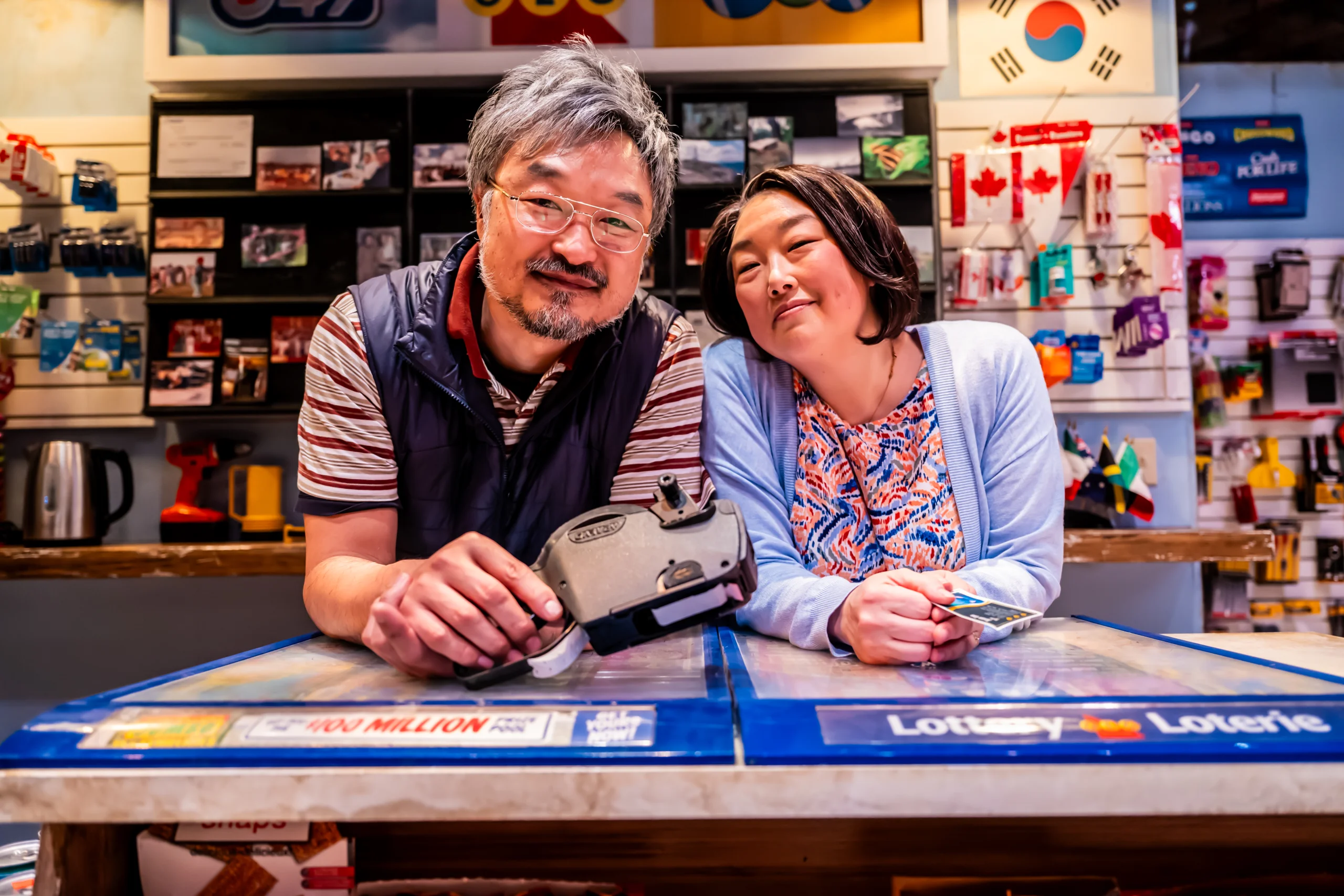 A man and a woman at a convenience counter smiling. 