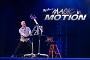 Man on stage with a moderately sized catapult. The text reads "Bill Blagg's Magic In Motion"