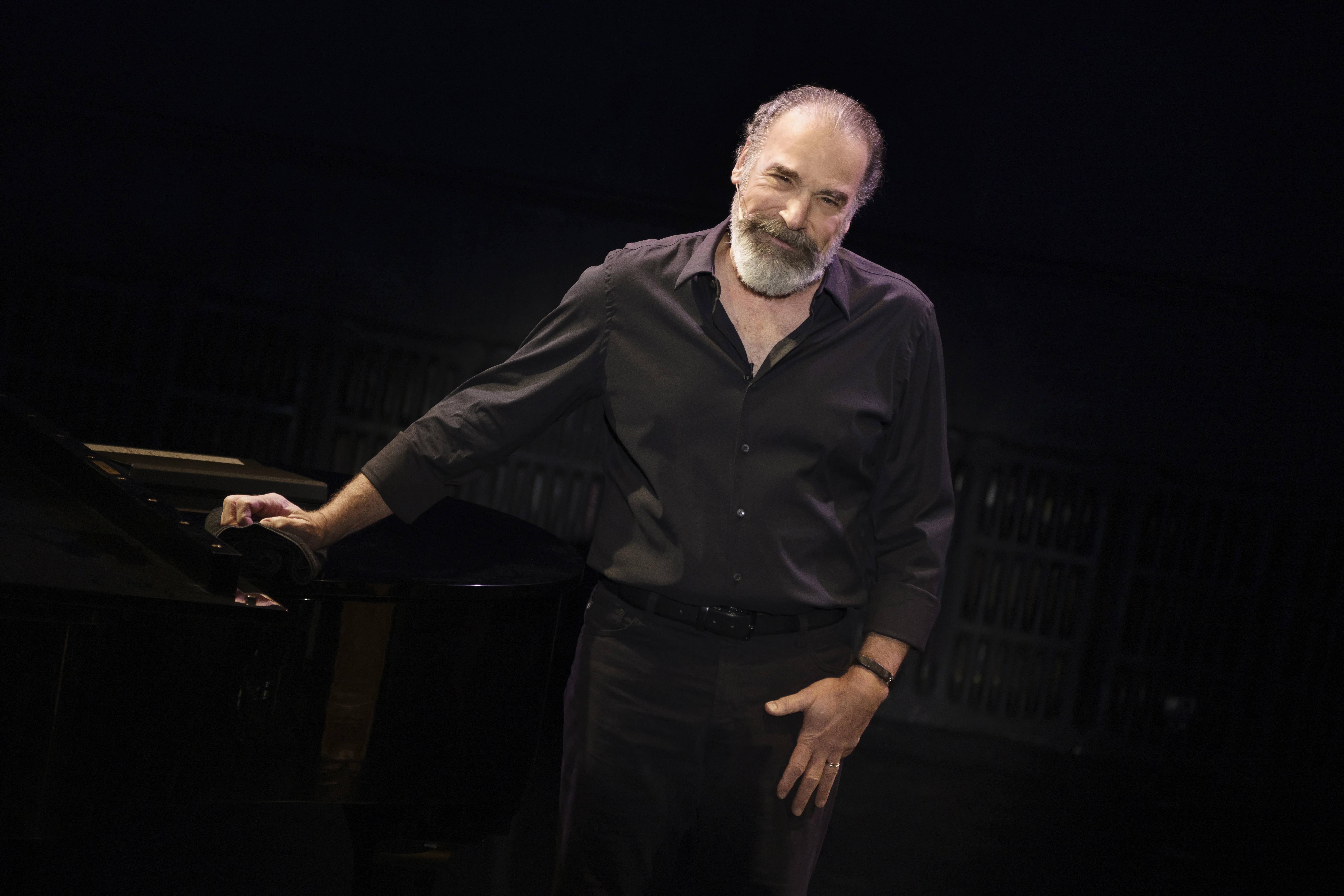 Mandy Patinkin gesturing on stage wearing black.