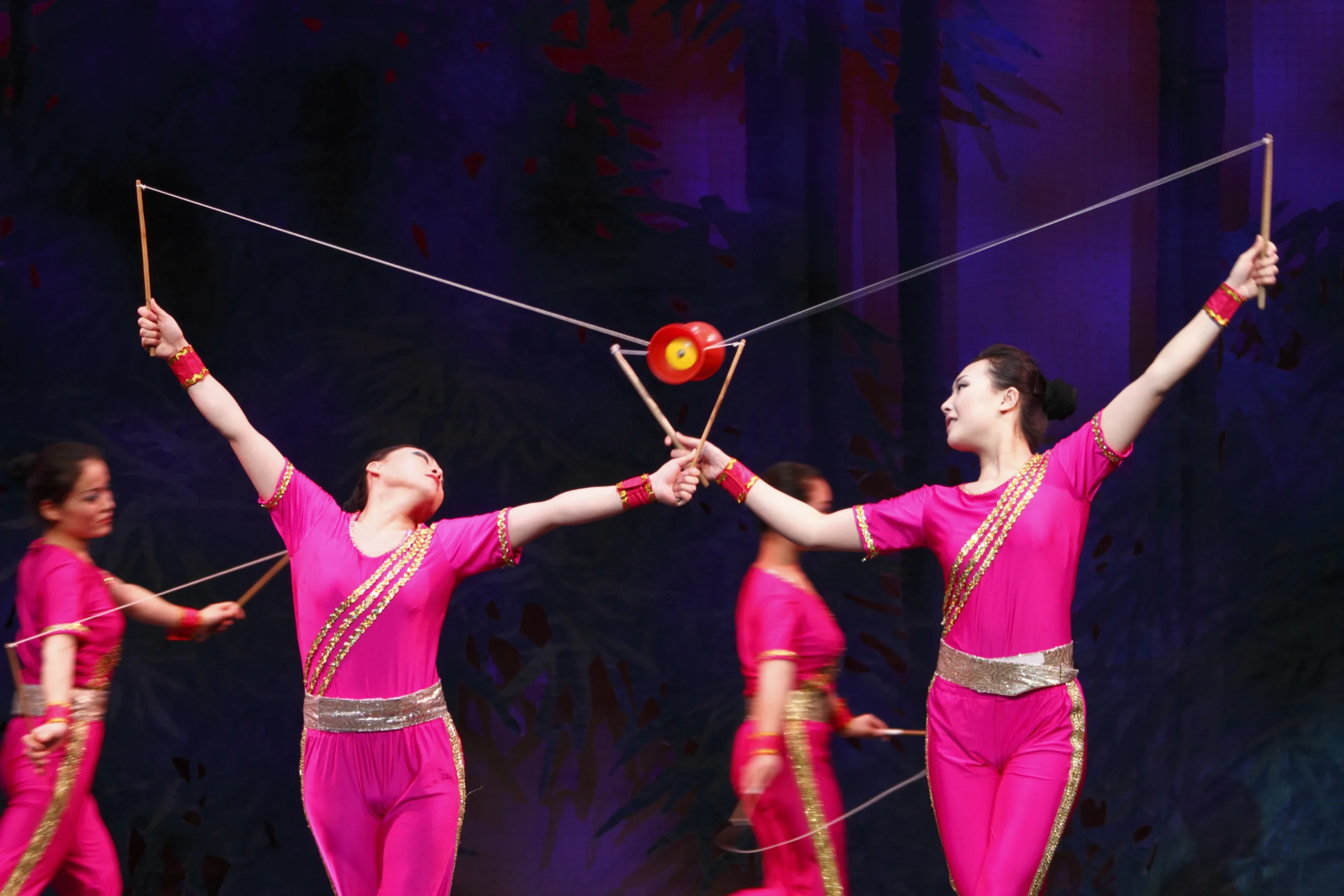 Acrobats perform with a two handed yo-yo above their heads.