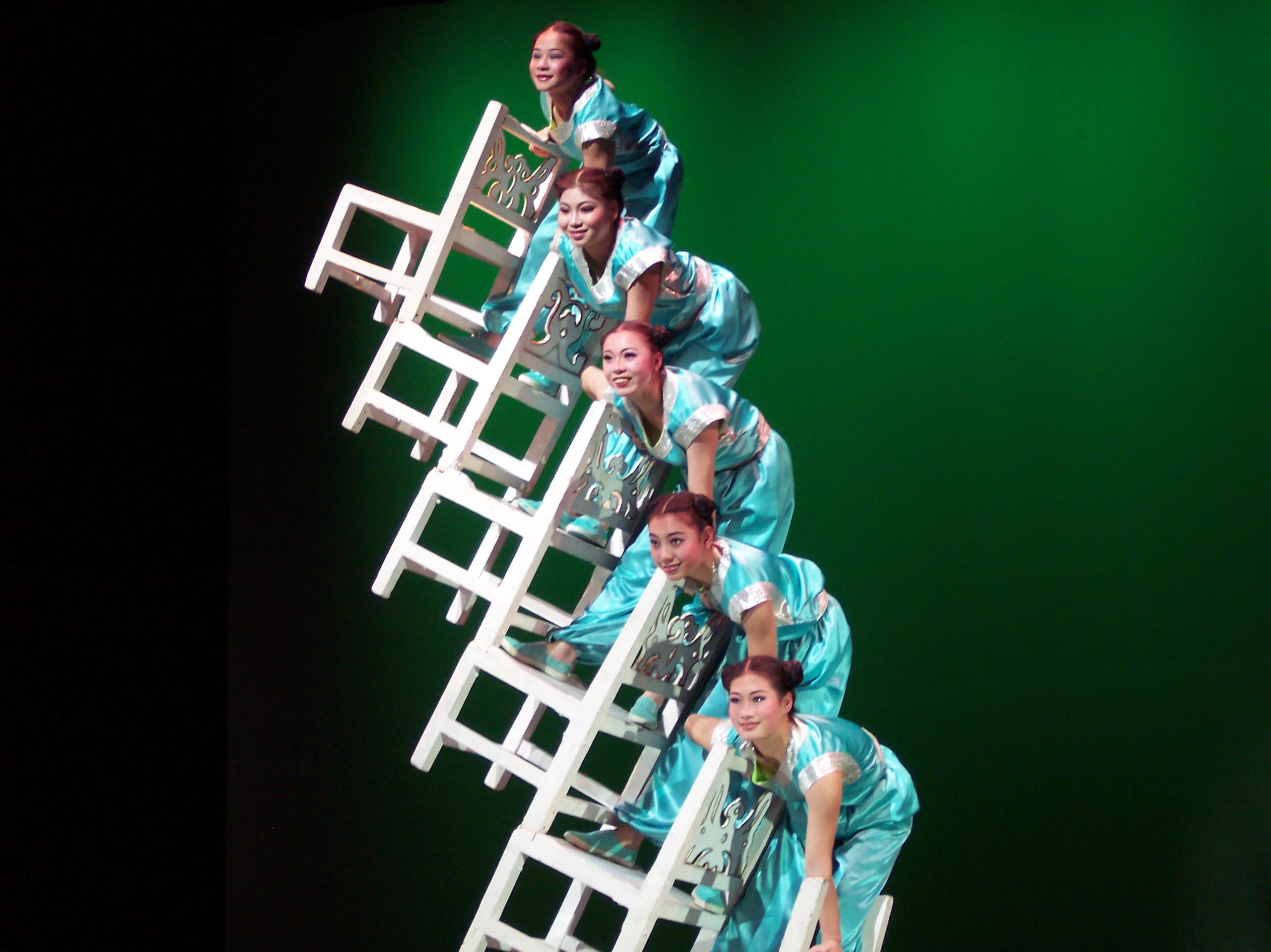 Acrobats stack chairs on top of each other and holding formation