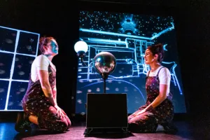 Two women onstage with a disco ball and bright lights