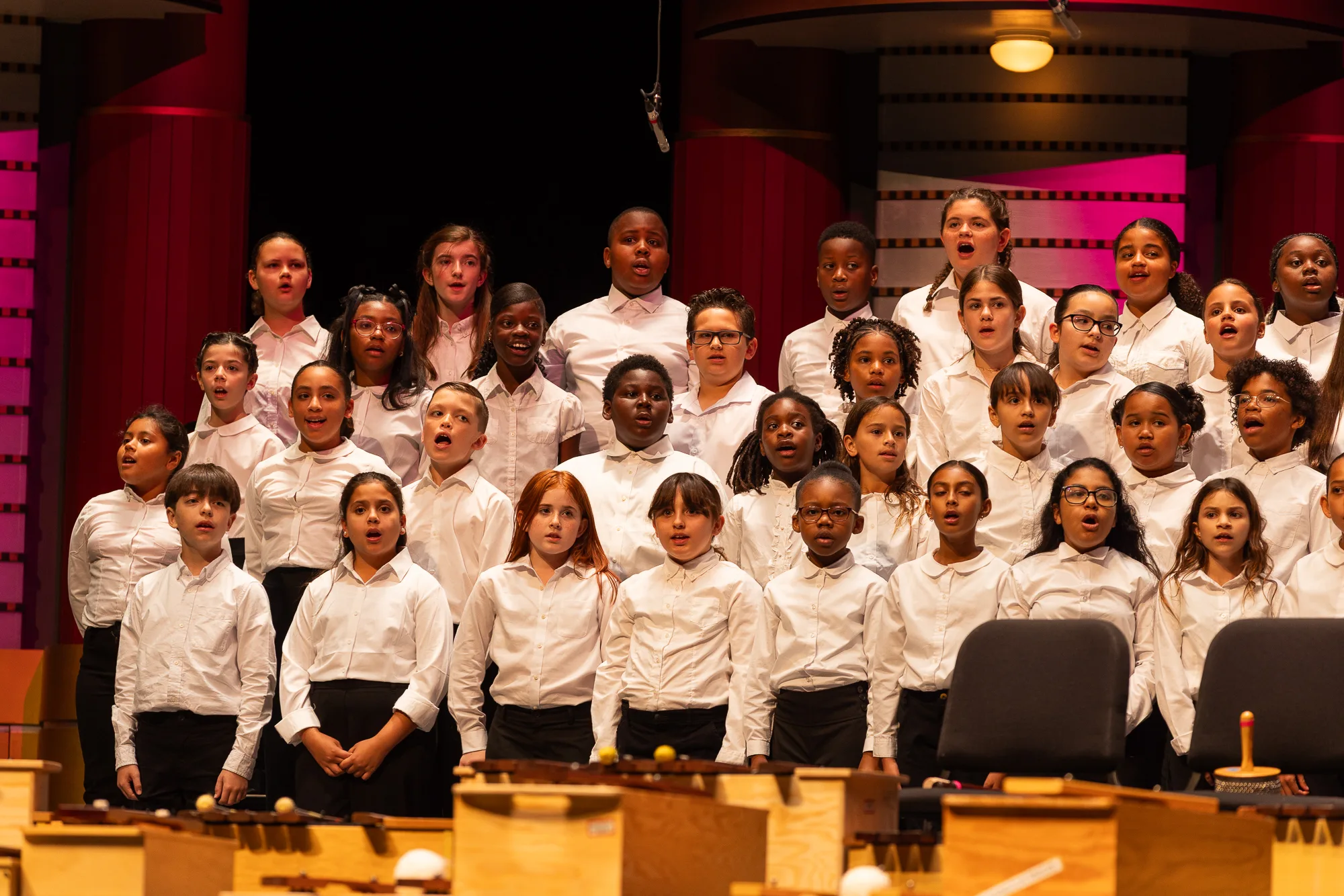 Spotlight on Young Musicians 2025 Children's choir on stage wearing white button down shirts and black pants.