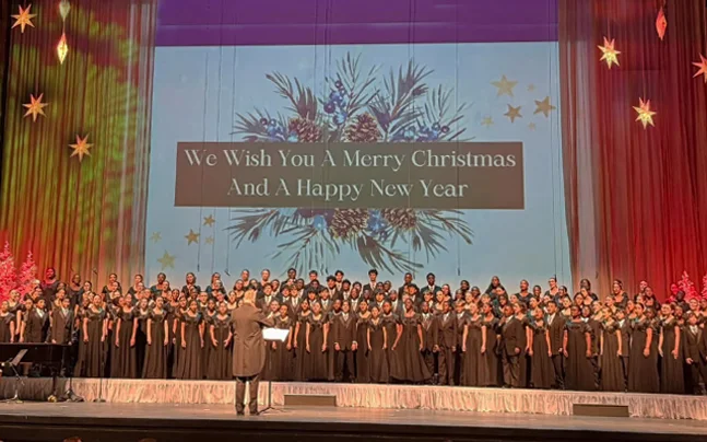 Young Singers choir wearing black on stage singing with a backdrop that says 
