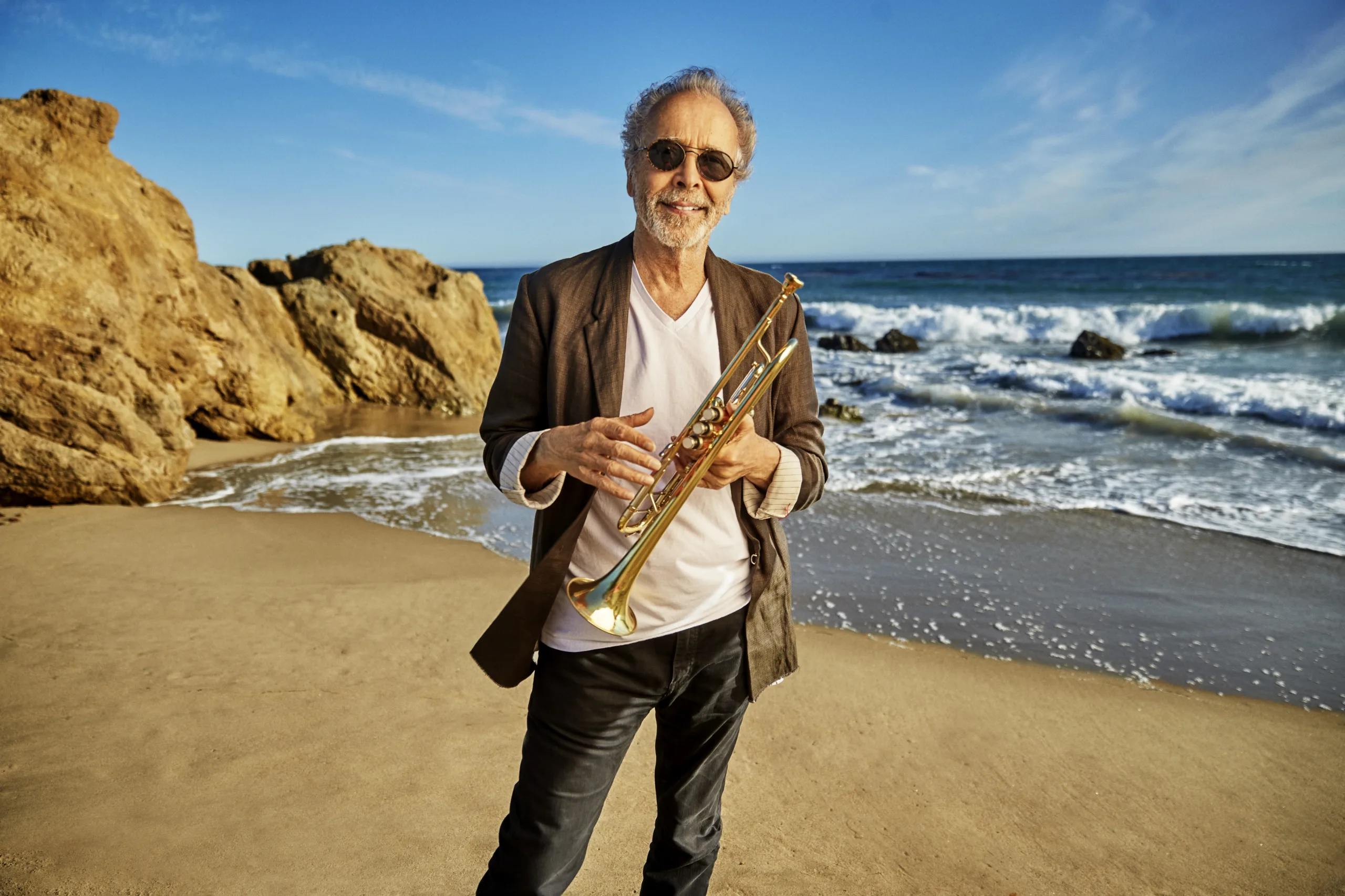 Herb Albert holding trumpet at the beach.
