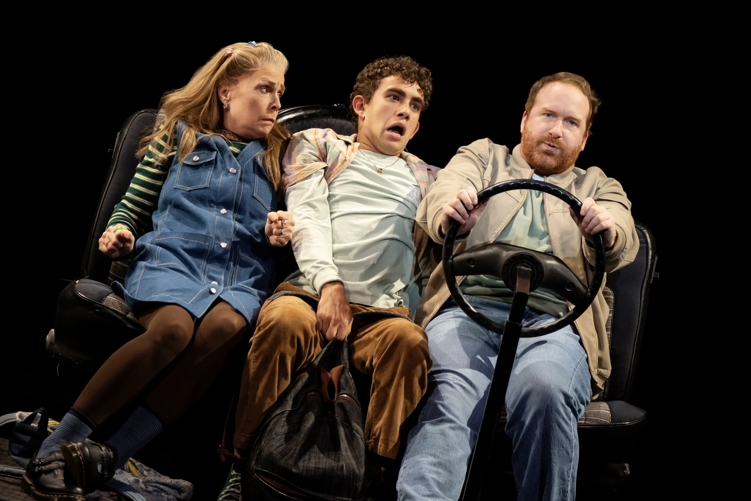 Kimberly, Seth and Buddy sitting together leaning heavily to the right with an unattached steering wheel in the middle.