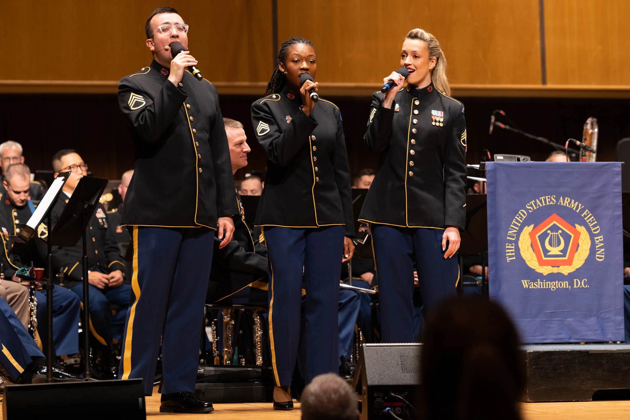 Three U.S. Army choir members singing in uniform.