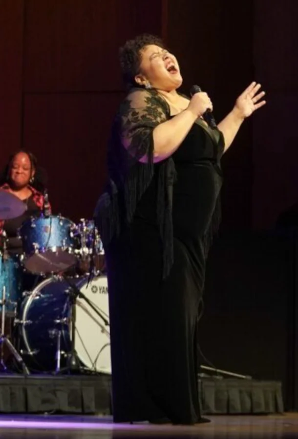 woman at microphone belts out singing.