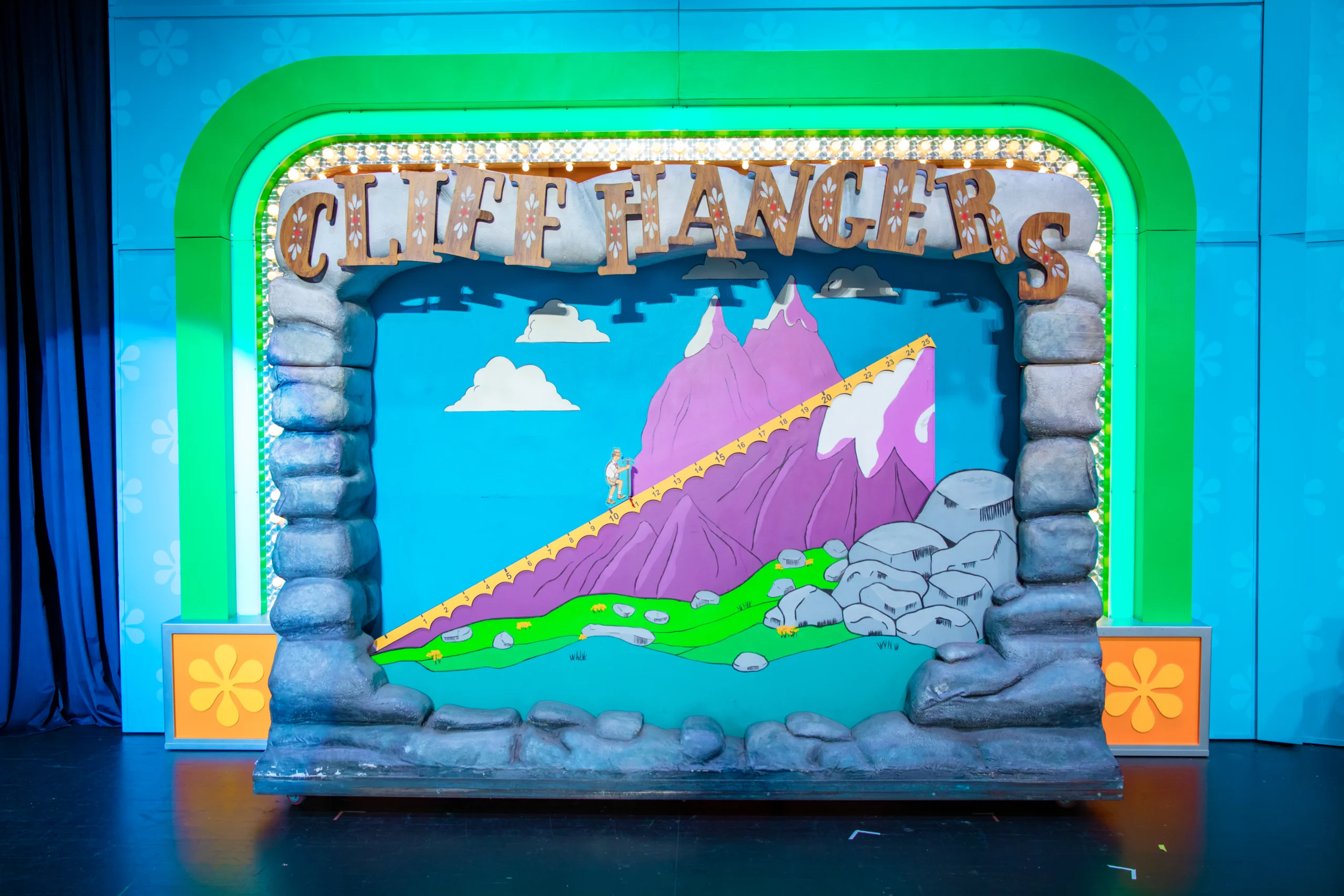 Colorful game set titled 'CLIFF HANGERS' with a mountain-themed background, a climber figure on a winding path, and rock-like structures framing the scene. The set features bright green and blue colors with decorative elements.