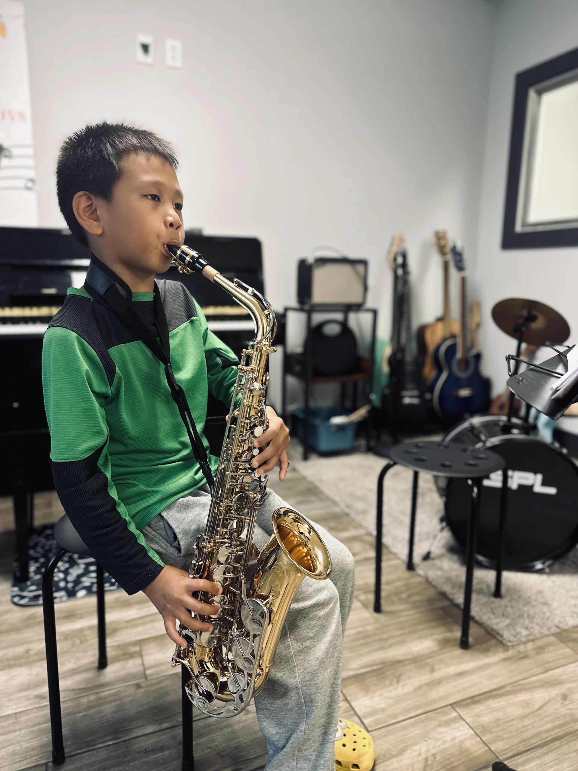 Young student playing saxophone in music studio.
